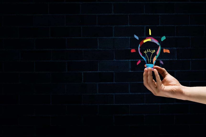 Male hand on dark background showing drawn light bulb