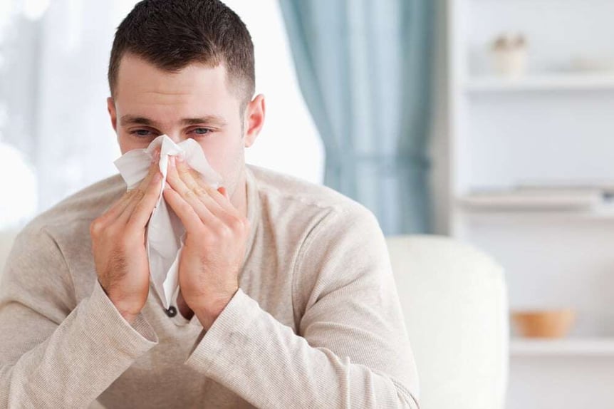 Man blowing his nose in his living room